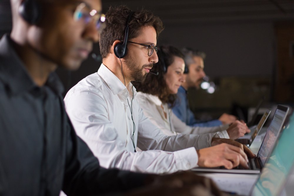 Professional software developers working on computers in a modern office, coding and collaborating on technology projects, focused teamwork in a tech workplace environment.